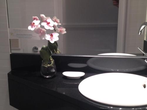 a bathroom with a sink and a vase with flowers at Hôtel Elysées Flaubert in Paris