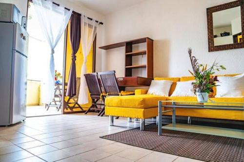 uma sala de estar com um sofá amarelo e cadeiras em Bel appartement T2 * Netflix * Terrasse* Parking em Kourou
