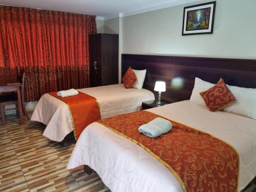 Habitación de hotel con 2 camas y mesa en Hotel Los Nogales en Cajamarca