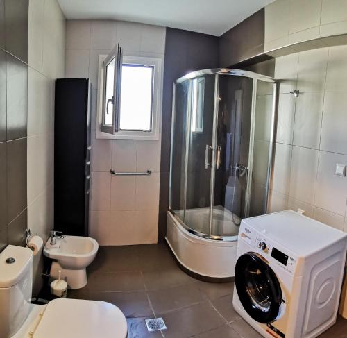 a bathroom with a shower and a washing machine at Seaside Serenity Kefalos in Kefalos