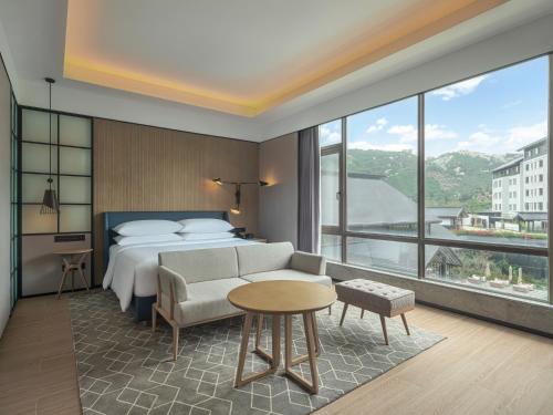 MaomingにあるSheraton Maoming Hot Spring Resortのベッドと大きな窓が備わるホテルルームです。