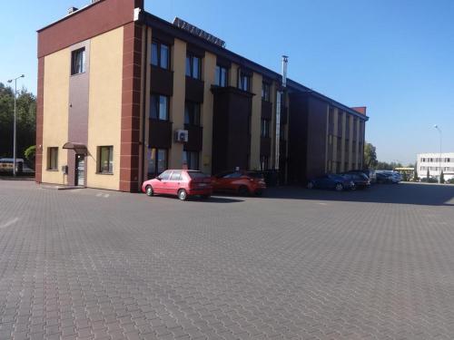 a building with cars parked in a parking lot at Gościniec Biznesowy in Dąbrowa Górnicza