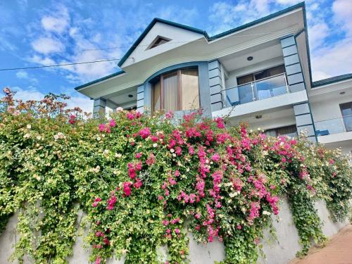 una casa con flores rosas delante de ella en Guest House Botanical Paradise, en Mtsvane Kontskhi