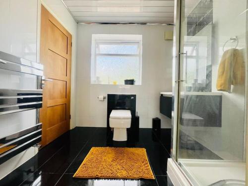 a bathroom with a toilet and a glass shower at Spacious 5 Bedroom house with free parking by Hostaguest in Luton