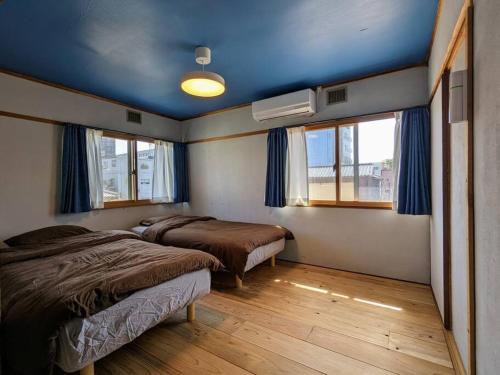 two beds in a room with blue ceilings and windows at アブラサカスペース in Nara