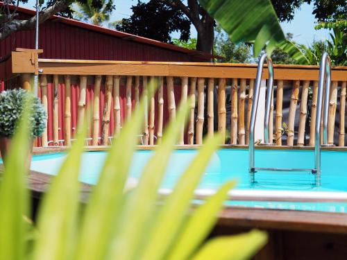 une clôture en bois à côté d'une piscine avec une chaise dans l'établissement S'cale TropiKal - Gite cosy avec piscine privée, à Petit-Canal