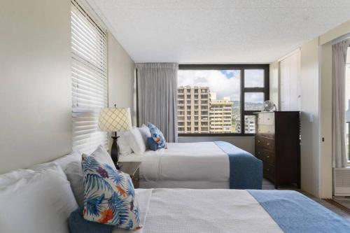 Habitación de hotel con 2 camas y ventana en Ala Wai Suite 1 Bed Canal View Condo, en Honolulu