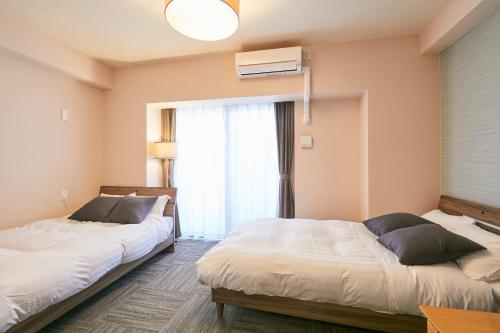 1 dormitorio con 2 camas y ventana en LINK HOUSE HOTEL - スマート無人ステイ - Unmanned design hotel en Fukuoka