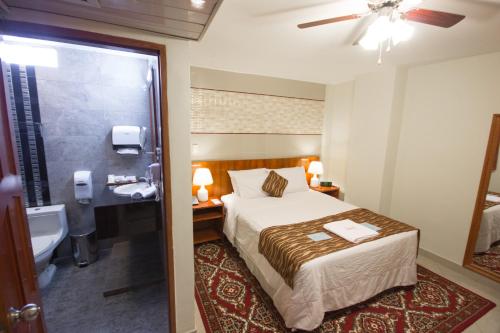 a bedroom with a bed and a bathroom with a sink at Samiria Jungle Hotel in Iquitos