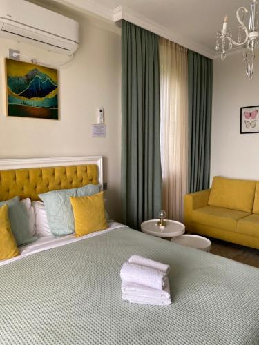 a bedroom with a large bed and a yellow couch at Guest House Botanical Paradise in Mtsvane Kontskhi