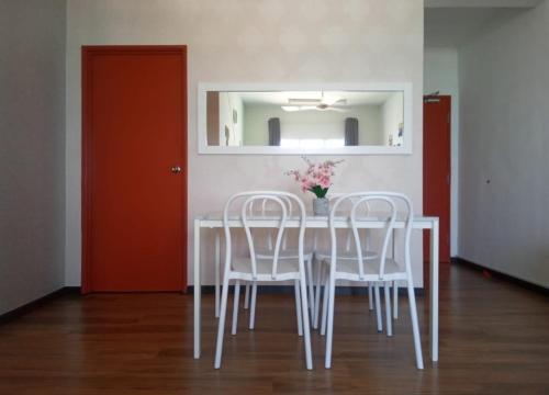 una mesa de comedor con sillas blancas y un jarrón de flores en Homestay 2007 Pangsapuri Ladang Tok Pelam Kuala Terengganu, en Kuala Terengganu