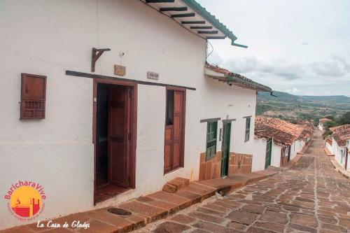 un edificio blanco con puertas de madera en una calle en La Casa De Gladys, en Barichara