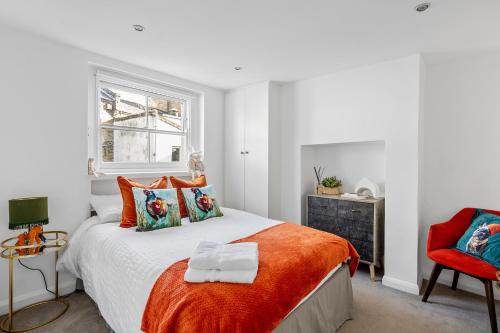 a bedroom with a bed with an orange blanket at Kensington two floor mews house in London