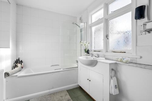 a white bathroom with a bath tub and a sink at Kensington two floor mews house in London
