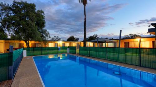 a swimming pool at night with a fence and trees at Cootamundra Gardens Motel in Cootamundra