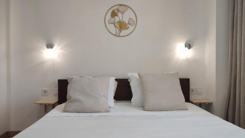 a bed with white pillows and a clock on the wall at Zen Guest House - Museu do Bonsai in Sintra