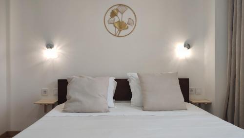 uma cama com almofadas brancas e um relógio na parede em Zen Museu do Bonsai em Sintra