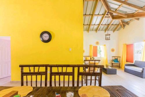 una habitación con una pared amarilla con un reloj en la pared en Sunflower village villa girasoles en Jarabacoa