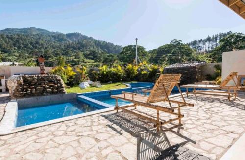 a patio with two chairs and a swimming pool at Sunflower village villa girasoles in Jarabacoa