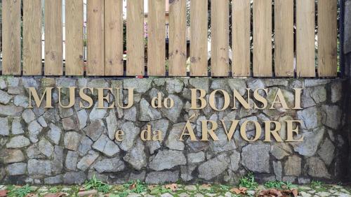 a sign on a stone wall next to a fence at Zen Guest House - Museu do Bonsai in Sintra