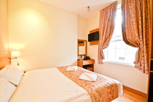 a bedroom with a bed and a window at Kings Cross Inn Hotel in London