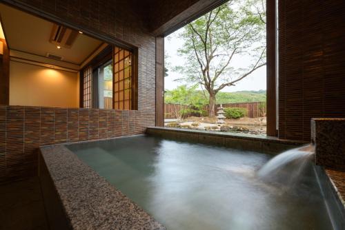 a swimming pool in a brick house with a waterfall at Onogawa Onsen Kajikaso in Yonezawa