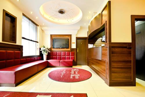 a waiting room with a red couch and a television at Kings Cross Inn Hotel in London