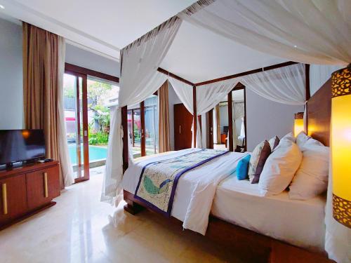 a bedroom with a canopy bed and a television at Seminyak Icon - by Karaniya Experience - CHSE certified in Seminyak