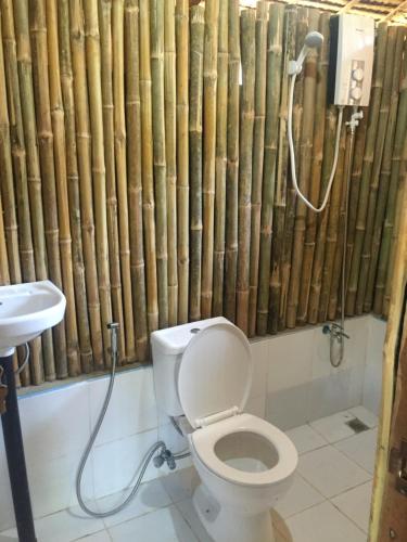 a bathroom with a toilet and a bamboo shower curtain at Coco Garden Villas in El Nido