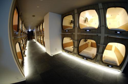 a hallway of an airplane with a row of windows at Capsule and Sauna New Japan EX (Male Only) in Hiroshima