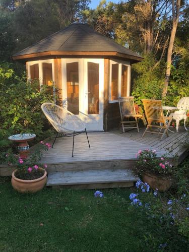 a deck with chairs and a gazebo at La Casita Waiheke in Oneroa