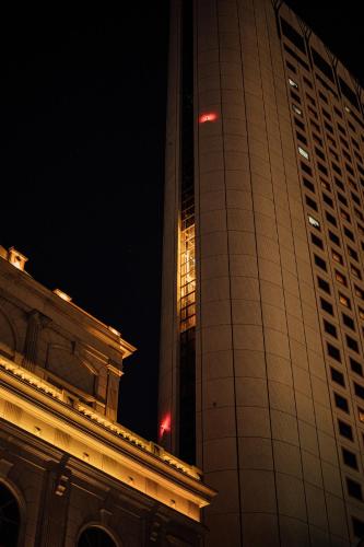 a tall building with its lights on at night at Lotte Hotel World in Seoul