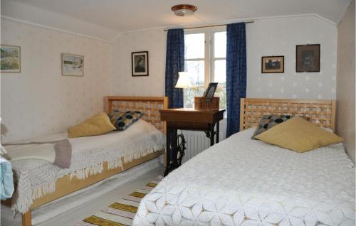 een slaapkamer met 2 bedden, een bureau en een raam bij 2 Bedroom Amazing Home In Charlottenberg in Charlottenberg