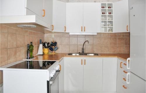 una cocina con armarios blancos y fregadero en Amazing Home In Kristinehamn With Wifi, en Rådetorp