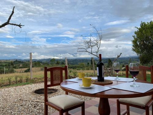 a table with a bottle of wine and two glasses at La cabaña, a 15 minutos de Paipa in Sotaquirá