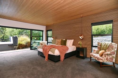 Bridle Path Retreat - Christchurch Holiday Homes في كرايستشيرش: غرفة نوم بسرير كبير وكرسيين