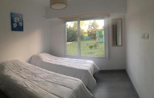 two beds in a room with a window at Casa Agustín in Balneario Claromecó