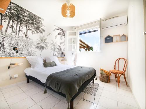 a bedroom with a bed with a palm tree mural at Villa familiale, piscine privée, classée 3 étoiles in Sainte-Rose