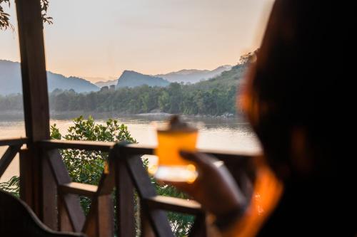 a person sitting at a table looking out over a river at Ock Pop Tok Mekong Villa in Luang Prabang