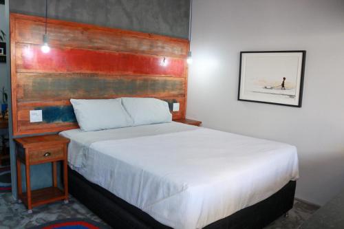 a bedroom with a bed and a wooden headboard at Agrega - Pousada com Piscina Peró entre Cabo Frio e Búzios in Cabo Frio