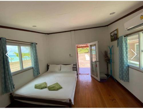 a bedroom with a bed and two windows at Koh Ngai Seafood in Ko Ngai