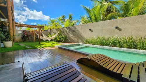 a swimming pool with a bench and a hammock at Kai Milagres Beach House in São Miguel dos Milagres