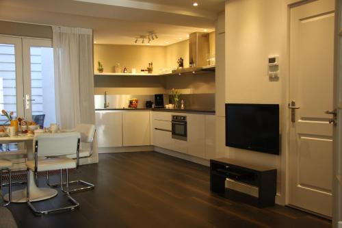 a living room with a table and a kitchen with a television at B&B Keizers Canal in Amsterdam