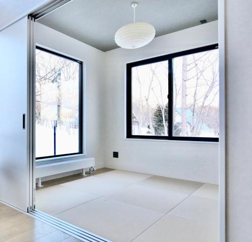 a room with white walls and windows and a mirror at DREAM LIFE Onsen Villa in Niseko