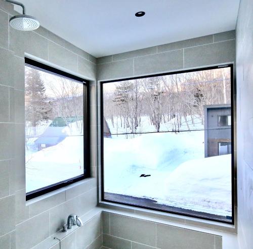 a bathroom with two windows and a snow covered yard at DREAM LIFE Onsen Villa in Niseko