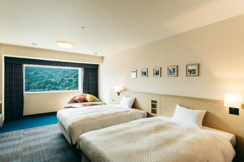 別府市にある亀の井ホテル 別府のベッド2台と窓が備わるホテルルームです。