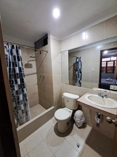 a bathroom with a toilet and a sink and a shower at Hotel Alpamayo Guest House in Huaraz