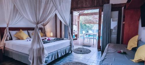 a bedroom with two beds and a door to a patio at Akasia Villas in Gili Islands