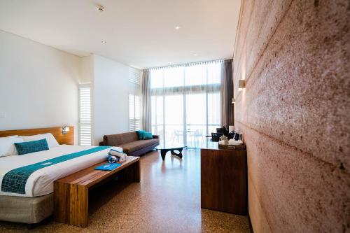 Mantarays Ningaloo Beach Resort في إكسماوث: غرفة نوم بسرير واريكة في غرفة