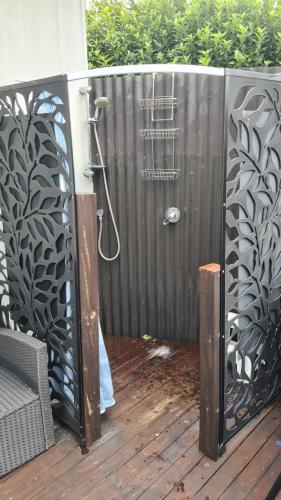 a shower in a black fence with a shower at Rowling Road Studio in Kaiteriteri